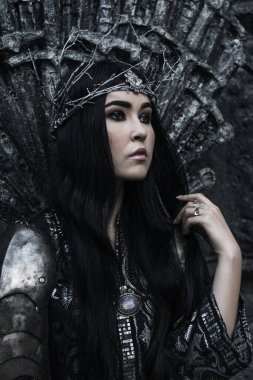 Zırhlı güzel savaşçı prenses bir kılıç tutuyor. Fantezi cadı şövalye siyah saçlı kadın çelenk giyiyor. Peri masalı gotik kraliçesi.