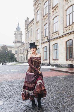 Eski bina, kürk manto, saç örgüsü, akşam makyajı, mavi gözler, kar, eski bina yakınlarında esmer ve silindir şapkalı güzel bir kadının eski moda portresi.