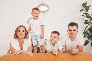 Ebeveynler oynuyorlar, çocuklarıyla eğleniyorlar. Yatak odasında, yatakta birlikte mutlu bir aile..