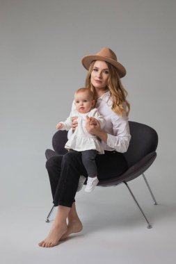 Stüdyoda sandalyede oturan güzel anne ve kız, sıradan bir aile görünüşü.