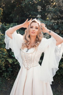 Ortaçağ tarzı beyaz elbiseli, mavi gözlü güzel sarışın elf kadın beyaz çiçeklerin içinde, fantezi prensesi