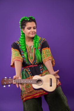Açık yeşil saçlı, ukulele çalan hippi kadının stüdyo portresi.