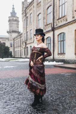 Eski bina, kürk manto, saç örgüsü, akşam makyajı, mavi gözler, kar, eski bina yakınlarında esmer ve silindir şapkalı güzel bir kadının eski moda portresi.