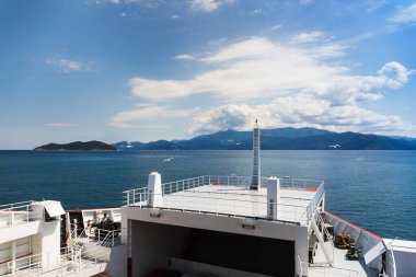 Yunanistan 'da turist macerası rengarenk yaz manzarası, feribotun yanından manzara, açık deniz mavi su, martılar, ada, dağlar, orman, bulutlu mavi gökyüzü