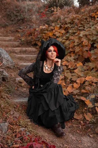 Рыжая Женщина Ведьма Черном Платье Остроконечная Шляпа Сидит Лестнице Осеннем — стоковое фото
