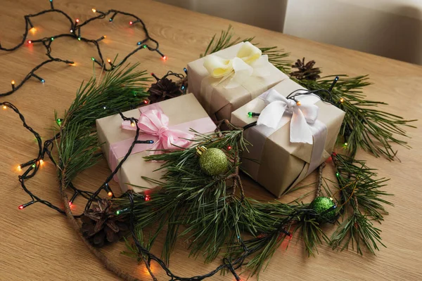 用黄色 粉色和白色缎带 松枝和木制桌子上的花环制作的圣诞礼物 — 图库照片