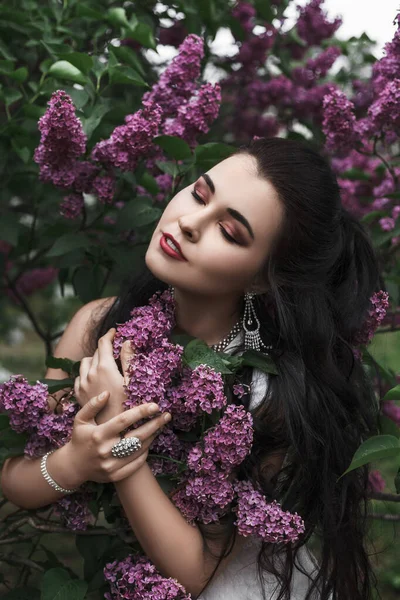 紫丁香花中美丽性感的黑发女子的春天户外肖像 长长的白色连衣裙 — 图库照片