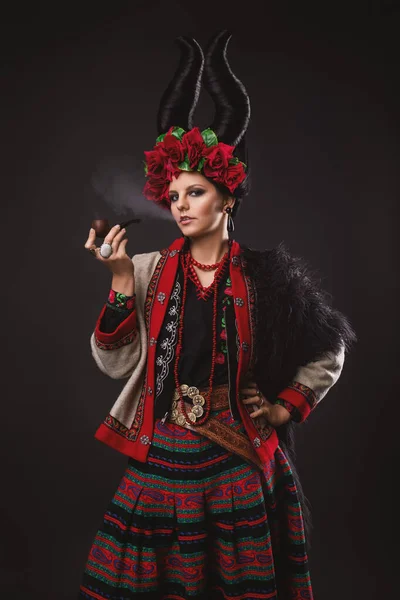 伝統的なウクライナの衣装の美しいブルネット女性 花輪と角が黒いスタジオの背景に立っています — ストック写真