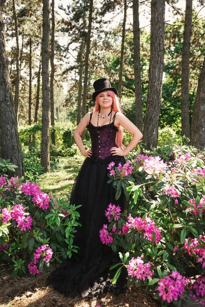 Piękna Kobieta Różowymi Włosami Cylindrze Wieczorowej Czarnej Sukience Gorsetem Ogrodzie — Zdjęcie stockowe