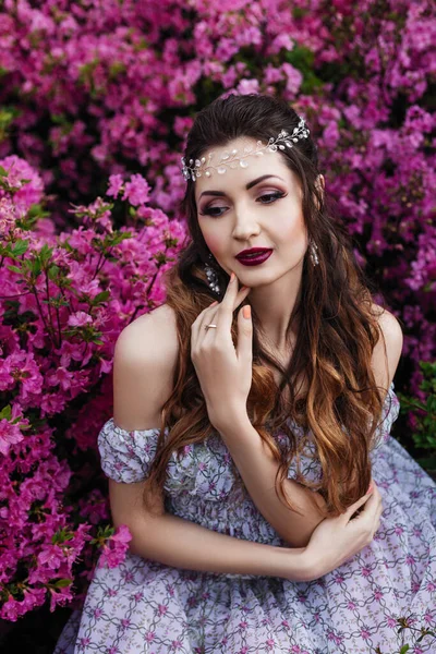 一个美丽的黑发女人 卷曲的头发 身穿浅色长裙 头戴皇冠 站在百合花丛中的春天画像 — 图库照片
