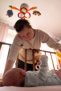 Kafkasyalı anne yeni doğan bebeğini yatakta kontrol ediyor.