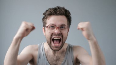 Neşeli olgun adam yumruklarını kaldırıyor. Başarı ya da piyangoda kazanmak. Kopyalama alanı oluşturun. Yumruklarını kazanan gibi sıkıyorsun.