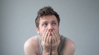 Korkmuş beyaz adam korkudan titriyor, kameraya korkmuş ve güvensiz görünüyor. Panik içindeki korkmuş adam endişeli, parasız.