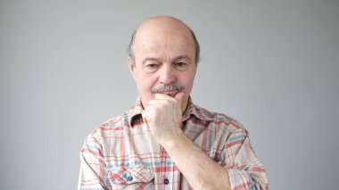 Son sınıf düşünceli bir adam çenesini tutar ve düşünceli bir şekilde kenara bakar planlar yapar. Yakışıklı büyükbaba bir şeyler düşünüyor.