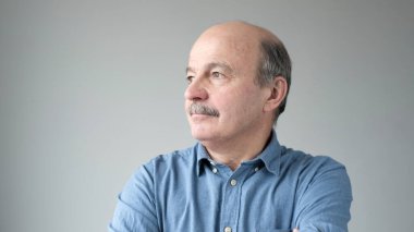 Gülümseyen olgun bir adamın portresi gri arka planda dikilip duruyor..