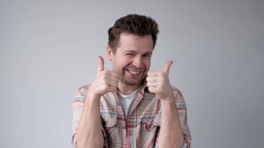 The European young man gives a thumbs up, approving the choice. Studio shot clipart