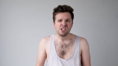 Avrupalı genç adam agresif davranıyor, kızgın bir yüz ifadesi takınıyor ve birini tehdit ediyor. Stüdyo çekimi