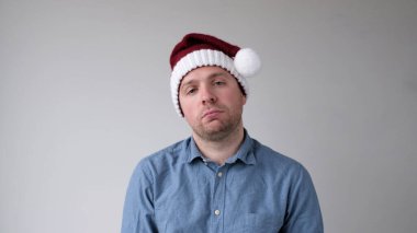 Yeni yıl şapkalı üzgün ve kederli Avrupalı genç adam kameraya kasvetli bir şekilde bakıyor. Yeni yıl kutlamalarında hayal kırıklıkları. Stüdyo çekimi