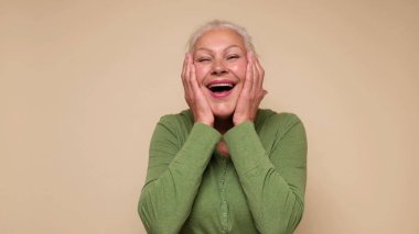 An elderly European woman is laughing. Studio shot clipart