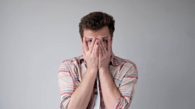 Enerjisi olmayan yorgun Avrupalı genç adam elleriyle yüzünü kapatıyor. Hiç olumlu duyguları yok. Stüdyo çekimi