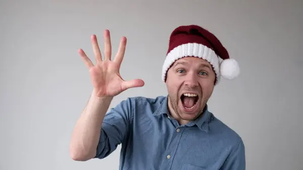 stock image Funny Man in a New Years Hat Counts Fingers, like Shows Numbers. Studio shot