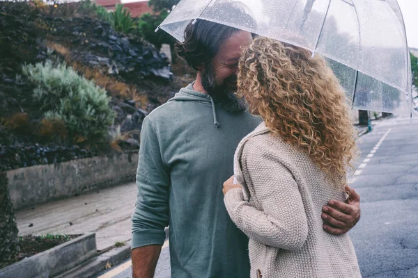 这对夫妇在雨天享受户外休闲活动 在透明的雨伞下拥抱和亲吻 道路上的城市背景 爱情和男女关系的概念 — 图库照片