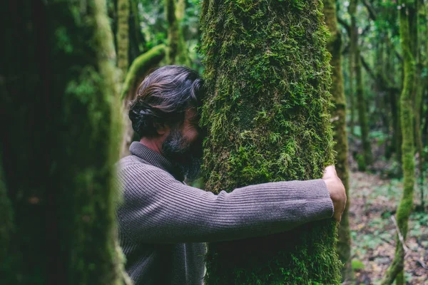 緑のマスクで木を抱いている男のサイドビュー 自然愛好家や環境の概念 気候変動と地球温暖化の停止 地球の日のお祝い 森の中の男の結合トランク — ストック写真