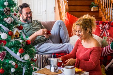 Mutlu çift, aile babası ve kadın, Noel sabahı evde birlikte kahvaltı ederken eğleniyor. Xmas ağacı ve kahve zamanı. Aralık etkinlik sezonu. Olgun kadın ve koca, boş zamanların tadını çıkarırlar.