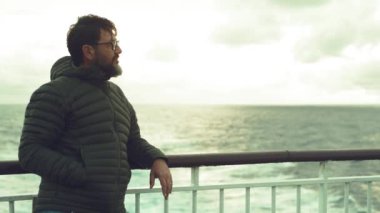  Okyanusta gün batımında teknenin güvertesinde duran ve hayranlık duyan bir adam. İnsanlar ve seyahat konsepti, tekne gezisi feribot gezisi. Gezgin tatilde. Açık havada eğlenen yolcular
