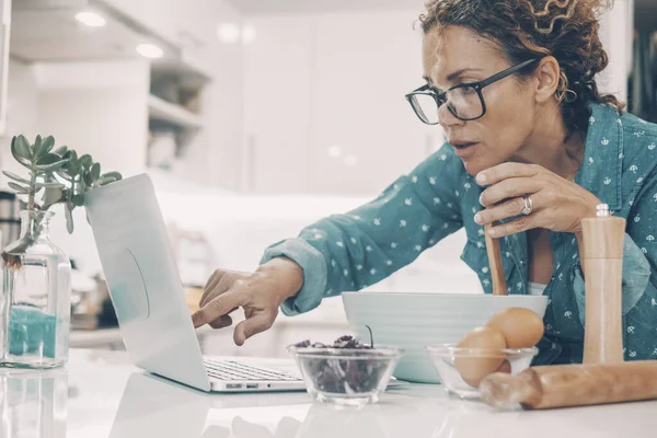 Kvinna Matlagning Tårta Hemma Med Hjälp Laptop För Recept Och — Stockfoto