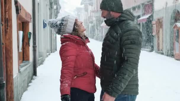 寒假期间 男人在雪地里亲吻一个女人 两个恋爱中的人在浪漫的白雪城里相爱 情侣们在户外接吻永远的关系概念生命 — 图库视频影像