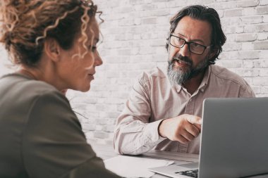  man explain concept at work to a woman sitting at the desk. Business couple at office using laptop together, Lawyer and client. Modern business people. Back view of female and male working together