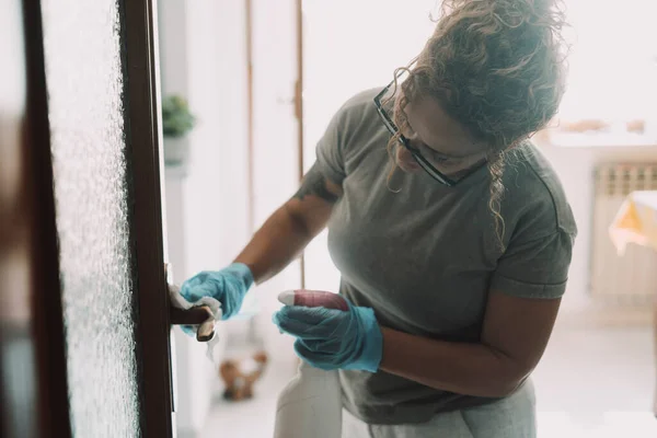 Domestic work at home. woman cleaning the door in apartment with spray and gloves. Housewife job. Hygiene and sanitize life place. Housemaid working and clean house surfaces. Concept of healthy