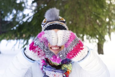 Happiness and joyful outdoor leisure activity people.  woman smiling and doing heart sign gesture with hands wearing warm knitted wool gloves in snow winter holiday vacation travel day concept
