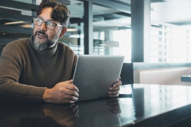 man working on laptop at the desk in empty office or coworking space with light in background. Scared for security account. Smart lifestyle people with online job. Looking on his side alone