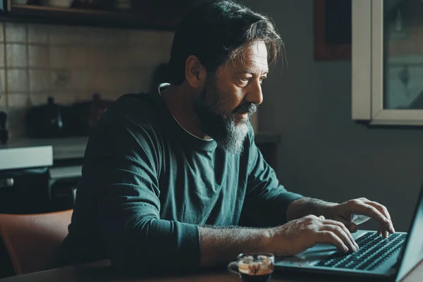 Mature male workaholic involved to work overtime, type report letter on laptop, search data at web. Ambitious young man in smart working develop career spend free time on computer at home alone indoor