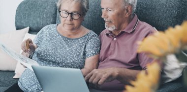 Energy gas bills cost problems in elderly lifestyle.  Worried couple of senior at home using laptop to pay bills and check documents. Mature man and woman with computer and online payment banking