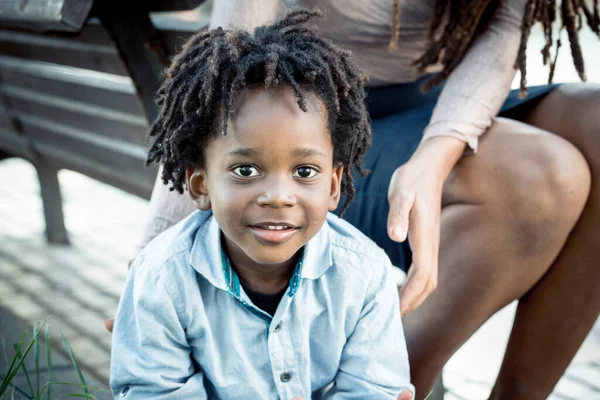 5歳の少年がカメラを見て微笑んだ 母親と屋外で時間を楽しむ小さな男の肖像画を閉じます 屋外レジャー活動で黒の母親と息子と家族 子供達は笑ってる アフリカ系アメリカ人 — ストック写真