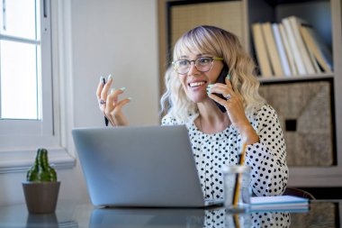 Happy woman in smart working telecommuting business activity. Modern online job for freelance people. Cheerful female doing phone call explaining ideas to clients. Attractive entrepreneur at work