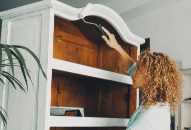 woman in indoor leisure hobby activity painting an old wooden cabinet furniture alone. Handyman female people concept work lifestyle. Independence. Restore and upcycling concept at home