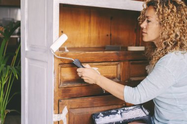  woman paint an old antique recycled cabinet at home in happy hobby indoor leisure activity alone. Concept of renovating and recycling sustainable. New home beginnings' lifestyle female people