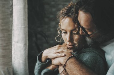 Evde romantik bir eğlence aktivitesinde olgun bir erkek ve kadınla aşk ve ilişki. Yetişkin bir adam pencerenin önünde dingin bir kadına sarılıyor. Aşk ve insanlar kucaklaşır