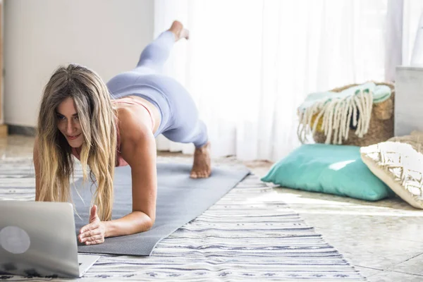年轻女性在家里锻炼 看她的个人笔记本电脑来学习或教授锻炼内容的创作者企业免费健康生活方式的概念 — 图库照片
