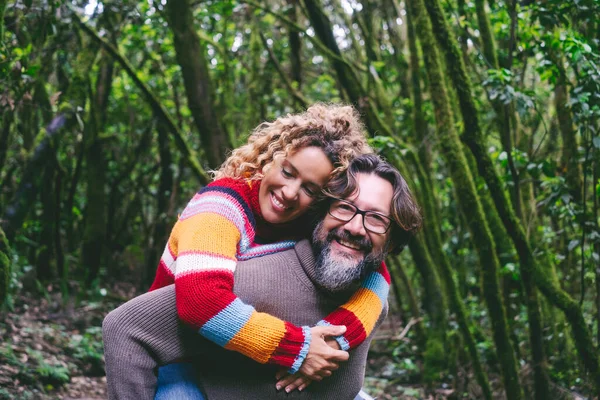 快乐的夫妻在绿林成林的公园里开心地微笑着 男人背着背着女人笑着恋爱和恋爱在户外休闲活动中结合在一起 旅行旅行目的地 — 图库照片