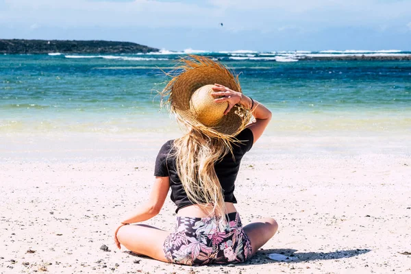 해변에서 일광욕을 즐기며 휴가를 보내는 여자의 모습을 돌이켜 밀짚모자를 실외에서 — 스톡 사진