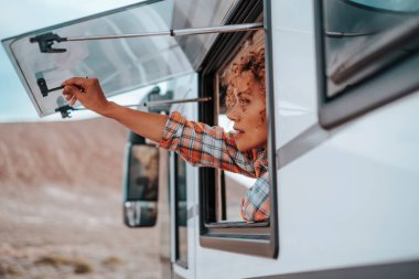 Seyahat eden bir kadın turist, karavanını varış noktasında açıyor. Tatil için araç kiralamak. Gezgin yaşam tarzı. Alternatif bağımsızlık, küçük ev konsepti. Vanlife yetişkin göçebe