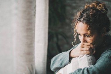 Cheated wife suffering from breakout relationship hugging a pillow at home in front of the window light. Love end and depression problems female. People and sadness. Fear of the future. Indoor scared clipart