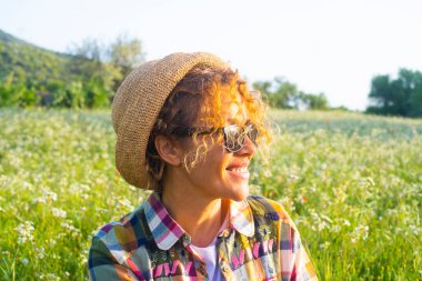 Çiçek koşu sezonunda arka planda yeşil çayır ile kırsalda gülümseyen neşeli genç bayanın resmi. Bahar ve yaz gününe hoş geldiniz. Açık havada boş zaman aktivitesi