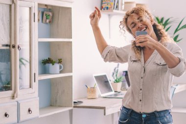 Mutluluk için dans eden ve şarkı söyleyen aşırı neşeli ve heyecanlı bir kadın. Başarı ve sağlıklı bir yaşam tarzı olan insanlar evde boş zamanlarında müzik ve dansla eğleniyorlar. Neşeli