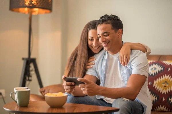 现代一对年轻夫妇在家里坐在沙发上玩手机游戏 一起玩乐 一起享受室内休闲活动 在公寓生活方式上年轻貌美的夫妇 — 图库照片